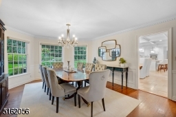 Dining Room with hardwood floors, three windows, deep base and crown moldings, chair rail, wainscoting, chandelier and French pocket doors which lead to the Kitchen