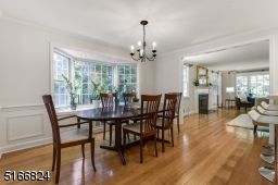Dining Room with hardwood floors, paneled walls, Bay window with a recessed light and a chandelier