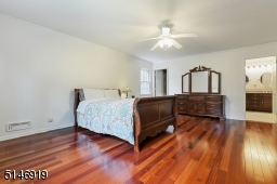 large primary bedroom en-suite features a cedar closet, walk in closet, wood floors