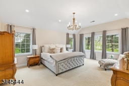 Primary Bedroom Suite features a vaulted ceiling, wall-to-wall  carpeting, a triple window overlooking the golf course, recessed lights, chandelier,  sitting area and dual fitted walk-in closets