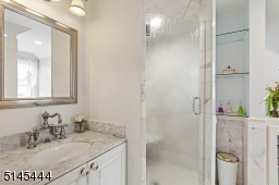 Full Bathroom (Bedroom 4) features white stone floors, a white sink with a marble top, a built-in dressing vanity, built-in glass storage cabinet and floating glass shelves