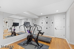 Exercise Room / Gym with double privacy doors, wood-look vinyl floors, recessed lights and two closets