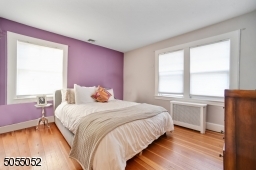 Primary Bedroom featuring hardwood floors, 2 exposures of windows including a double windowing overlooking the front yard, and 2 closets