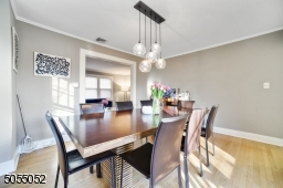 Dining Room featuring deep baseboard moldings, crown moldings, hardwood floors, modern chandelier