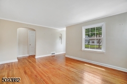 Spacious living room with crown molding, hardwood floors & wood-burning fireplace upon entrance.
