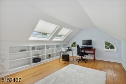 Third floor office with pine floors, wall of shelves and two skylights with pleated shades