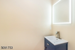 half bathroom located on 1st floor with contemporary blue vanity and touch screen mirror.