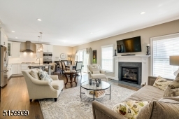 Family Room is an open concept to the Kitchen and Dining Area and features hardwood floors, a gas fireplace flanked by windows, crown molding and an open staircase