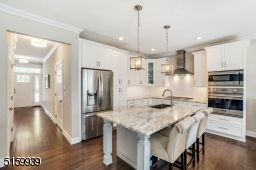 Kitchen with Viking stainless steel appliances including a 30" wall oven and 36" 5-burner cooktop, center island with seating for four, crisp white custom cabinetry including 42? upper cabinets, quartz counters, & subway tile backsplashes