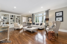Living Room featuring hardwood floor, crown molding, baseboard moldings, designer pendant light fixtures,2 sets of built-in bookcases with open shelving and under storage, also accessible to 2nd Home Office.