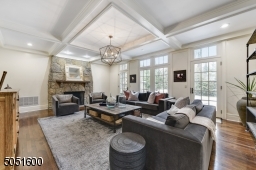 Family Room w/ access from front hall, Kitchen & Living RM featuring hardwood floors, baseboard molding, crown molding, coffered ceiling w/ recessed lights, chandelier, wall of windows overlooking patio & access to patio and stone (gas) fireplace