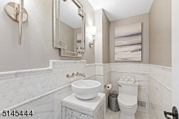Powder Room with white marble floors and walls, designer wall covering, unique vessel sink, decorative tiles and two modern sconces