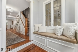Foyer features parquet floors, paneled walls, coat closet and an open staircase