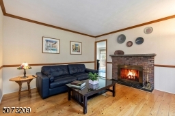 Den with wood burning fireplace and pegged hardwood flooring