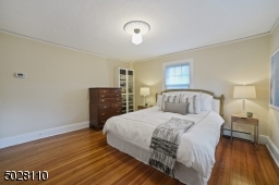 Bedroom 1 featuring hardwood floors, 2 exposures of windows, flush mount light fixture and double California closets