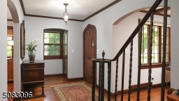 Arched oak door, graceful custom wrought iron staircase, hardwood floors, two guest coat closets