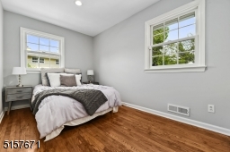 Bedroom 1 with hardwood floors, recessed lights, windows at two exposures and a double closet