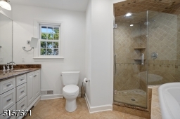 Primary Bathroom with tile floors, deep soaking tub, frameless glass enclosed shower, double marble top vanity, recessed lights and a floor to ceiling linen closet