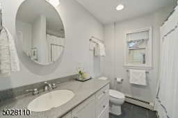 Full Hallway Bathroom featuring grey tiles, recessed lights, shower over tub with white subway tiles and custom beadboard built-in custom vanity with storage