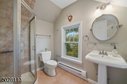 Full Bathroom featuring a glass-enclosed shower, built-in linen closet, pedestal sink and exposed brick wall