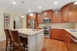 Chef's Eat-In kitchen featuring hardwood floors, custom wood cabinetry with soft close doors, crown moldings, granite countertops, island with seating, concealed storage and extra prep sink