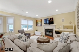 Family Room featuring hardwood floors, crown molding and a gas fireplace with white mantle and stone surround