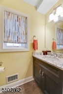 Powder Room featuring a wall-to-wall vanity with granite counter, sconce, mirror and a window