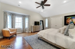 Primary Bedroom Suite featuring hardwood floors, tray ceiling, bay window with seating area, large walk-in custom fitted closet plus another double fitted closet