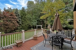 The deck overlooks private rear grounds with a natural privacy border of deciduous and evergreen foliage.