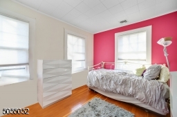 Bedroom 2 featuring hardwood floors, 2 exposures of windows and a closet
