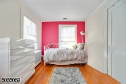 Bedroom 2 featuring hardwood floors, 2 exposures of windows and a closet