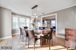 Dining Room featuring deep baseboard moldings, crown moldings, hardwood floors, modern chandelier