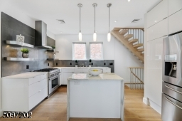Industrial-effect Italian backsplash tile and a marble waterfall island (Montclair Danby marble) with extra storage - stone procured and crafted locally. The rest of the kitchen is fitted with a white Caesar Quartz stone counter. High-end SS appliances.
