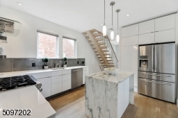 Industrial-effect Italian backsplash tile and a marble waterfall island (Montclair Danby marble) with extra storage - stone procured and crafted locally. The rest of the kitchen is fitted with a white Caesar Quartz stone counter. High-end SS appliances.