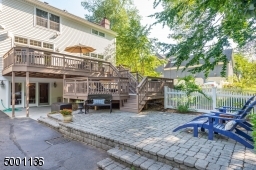 View of double tiered deck, lower level walk out, paverstone patio and fenced in grassy level yard