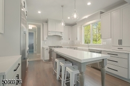 Center island with seating for 4, beadboard detailing and storage, recessed lights, glass pendant lights, bubble light fixture in Breakfast area with bay windows and recessed ceiling