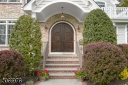 Bluestone walkway with brick border leads to Double solid wood, Speakeasy, Front Doors featuring curved wood surrounded by brick and stone, covered entryway with hanging lantern