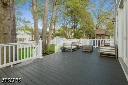 A large Hardi-Plank Deck overlooks the fenced-in level yard with play area / jungle gym, mature flower beds, trees and shed.