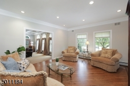 Bright and sunny living room that has newly refinished wood floors, recessed lighting and large windows.