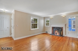 Spacious living room with crown molding, hardwood floors & wood-burning fireplace upon entrance.
