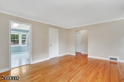 Spacious living room with crown molding, hardwood floors & wood-burning fireplace upon entrance.