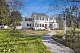 Covered Front Entry featuring recessed paneled molding, dentil molding and paneled wood front door with sidelights and brass kickplate