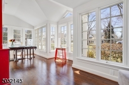 Sunroom / office featuring hardwood floors, vaulted ceiling, two exposures of floor-to-ceiling windows, and French door to private brick patio