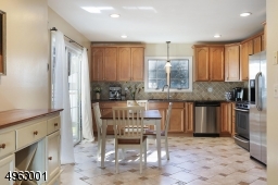 a spacious kitchen with high end stainless steel appliances, granite countertops, wood cabinetry, and breakfast area
