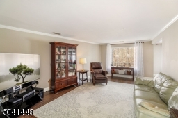 Enjoy the woodland and pond views from this roomy living room with crown molding and engineered hardwood flooring.