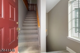 Entry view with new wall-to-wall carpeting on stairs that lead up to main level and down to lower level bonus room with newer full bath and direct garage access.