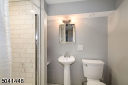 Newer full bath on lower level has Carrera marble subway-tiled stall shower and flooring.