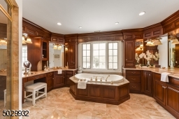 Bathroom with marble shower, countertops, and floor, 2 vanities, 2 sinks and custom cabinetry.