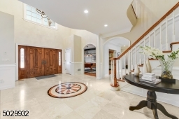 Grand 2-story entrance with 18' ceiling, marble floor, crystal chandelier, 2 coat closets, custom millwork, arched doorways, pillars, and curved staircase.