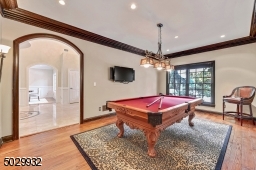 Bright living room with beautiful moldings, arched doorway, hardwood floor and double doors to great room.